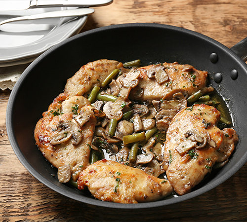 Grilled chicken breast with mushrooms in the black pan
