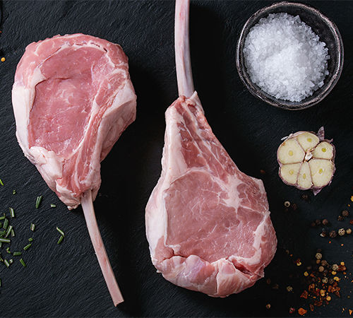 Fresh veal chops with garlic and salt on black board