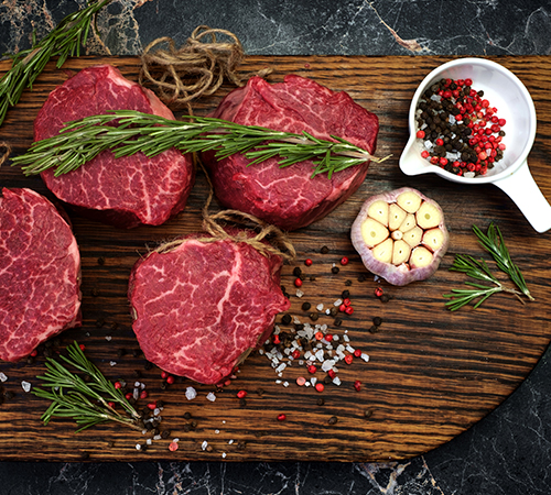 Filet mignon steaks spiced with rosemary and garlic on wooden board